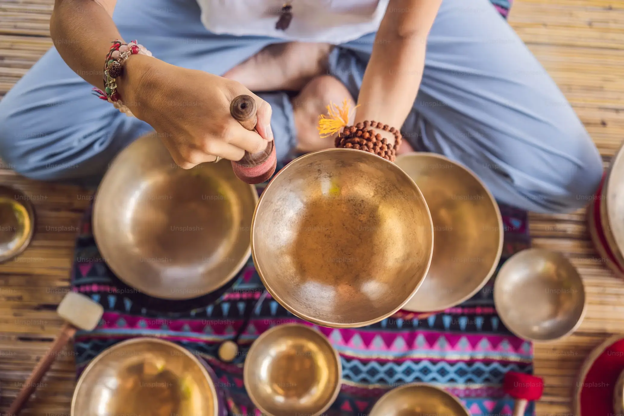 Close-up of a person playing a Tibetan singing bowl during a sound therapy session.